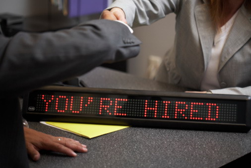 A person is sitting at a table with an electronic sign.